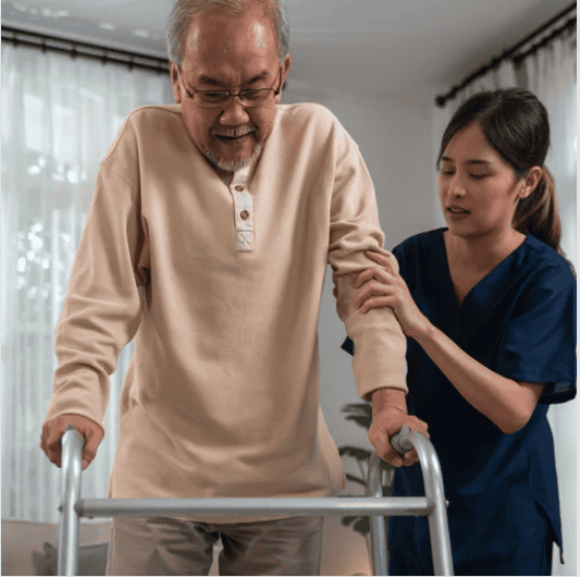 nurse helping elderly man walk with walker in his home