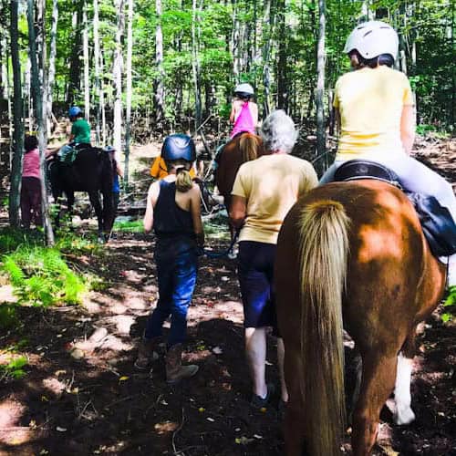 children riding horses being led by Reinbow Riding Center staff members