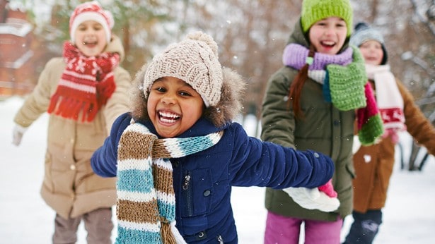 Happy kids playing outdoors with warm coats and snow pants thanks to Welcome to Winter.