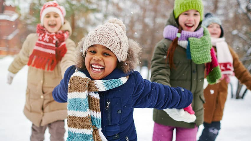 Happy kids playing outdoors with warm coats and snow pants thanks to Welcome to Winter.